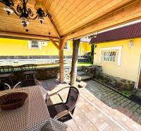 The garden of a family house in Vrbovce with a covered seating area and a yellow facade.
