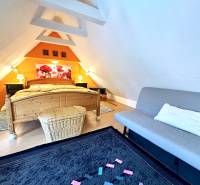 Attic bedroom in a family house with a wooden decor floor and an orange wall.