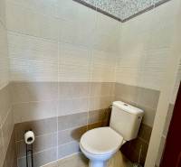 Bathroom in a 2-room apartment with a toilet, beige tiles, and decorative cladding.