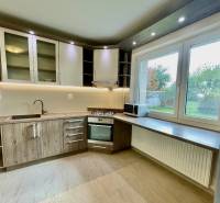 A kitchen unit in a 2-room apartment with a wooden decor floor and a large window.