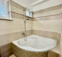 Corner bathtub in a bathroom with light tiles in a 2-room apartment.