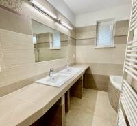 Bathroom in a 2-room apartment with a double sink and tiles in neutral shades.