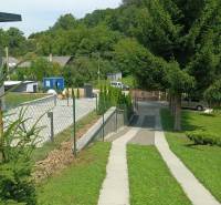 The sidewalk runs alongside the green lawn in Jasenovce on Jesenovce Street, suitable for residential plots.