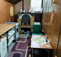 A kitchen with wooden decor, a tiled stove, and green furniture on the premises - living.