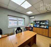 An office with a wooden floor, office furniture, and cabinets full of documents.