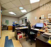 Office space with desks, a computer, a chair, and a floor with a wooden decor.