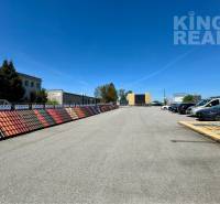 Parking lot with cars and displayed roofing at Petrovianska 284 in Prešov for commercial land.