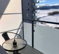 A balcony of a studio apartment in Poprad with a view of the snowy landscape and a residential complex.