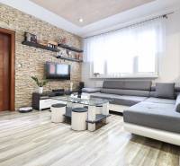Living room in a 3-room apartment with a wood-decor floor and a stone wall.