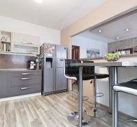 Kitchen in a three-room apartment with a wood-patterned floor and a bar counter.