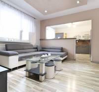 A room with a wooden decor floor, a sofa, and a glass table in a three-room apartment.