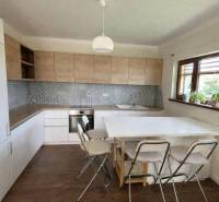 A kitchen in a family house with a wooden decor floor, a dining table, and chairs.
