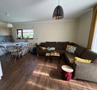 Living room with kitchen in a family house, wooden decor flooring, sofa and dining table.
