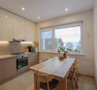 A kitchen in a 3-room apartment with a wooden decor floor, a dining table, and built-in appliances.