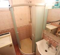 A bathroom in a 3-room apartment with a washing machine, shower, and sink.