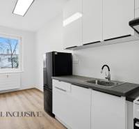 A kitchen in a 3-room apartment with a black refrigerator and a wooden decor floor.