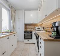 A kitchen in a 2-room apartment with white cabinets and a wood-patterned floor.