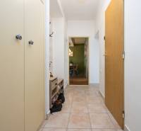 A hallway in a 2-room apartment with tiles, a built-in wardrobe, and a coat rack.