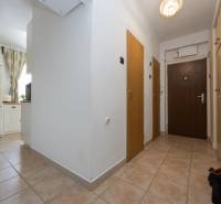 A hallway in a 2-room apartment with built-in wardrobes and tiles, view towards the kitchen.