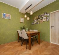 Dining area in a 2-room apartment with a green wall and a wooden decor floor.