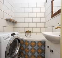 A bathroom with a washing machine and ceramic tiles in a 2-room apartment.