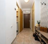 A hallway in a 2-room apartment with a tiled floor and built-in wardrobes.