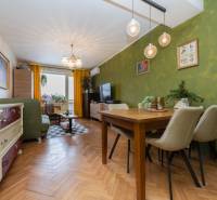 Living room in a two-room apartment with a wooden decor floor, green walls, and a dining table.
