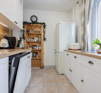 A kitchen in a 2-room apartment with white cabinets, wooden decor, and appliances.