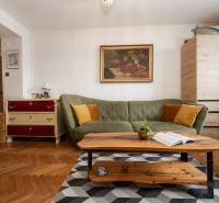 Living room in a two-room apartment with a wooden decor floor, a green sofa, and a painting.