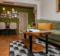 Living room in a two-room apartment with a sofa, table, and wooden decor flooring.