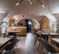 Historical gastro spaces with stone walls and brick vaulting, flooring with a wooden decor.