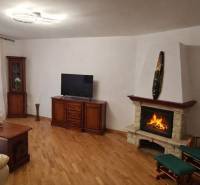 Living room in a 3-room apartment with a TV, fireplace, and wooden decor flooring.