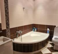 A bathroom in light tones with a corner bathtub in a 3-room apartment.