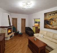 Living room in a 3-room apartment with a fireplace, sofa, and wooden decor flooring.