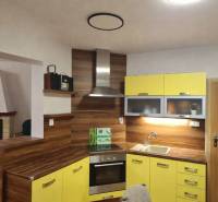 A kitchen in a 3-room apartment with a fireplace, yellow cabinets, and a floor with a wood decor.
