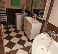 Bathroom in a 3-room apartment with a bathtub, sink, and washing machine, tiled floor.