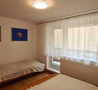 Bedroom in a 3-room apartment with beds, a television, two paintings, and a floor with a wooden decor.