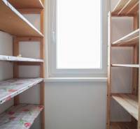 A compact pantry with wooden shelves and a window in a 3-room apartment.