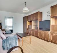 Living room in a three-room apartment with a wooden decor floor and older furniture.