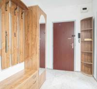 A hallway in a 3-room apartment with a coat rack, cabinets, and a mirror.
