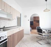 A kitchen with a dining table and cabinets, connected to the living room in a three-room apartment.