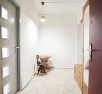 A bright hallway with ceramic tiles, a wooden table, and a chair in a 3-room apartment.