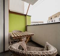 A balcony with rattan furniture and a green wall in a 2-room apartment, Trenčín, Hroznová.