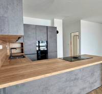 A kitchen in a family house with dark cabinets and a wood-patterned floor.