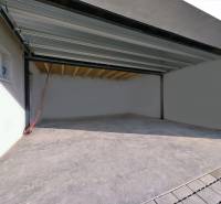 A garage of a family house in the Belža area of Belža with a concrete floor and open doors.