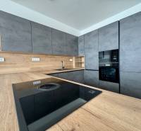 A kitchen in a family house with a wooden decor floor, gray cabinets, and a modern appliance.