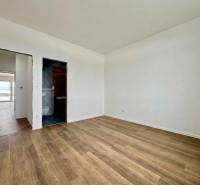 A room in a family house with a wooden decor floor and access to the bathroom.