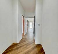 A hallway in a family house with a wooden decor floor and white walls.