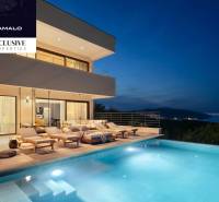 Villa with a terrace and pool, with a night view of the illuminated coastline.