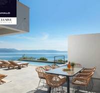 The terrace of the villa in Labin with a view of the sea, sunbeds, and a dining table.